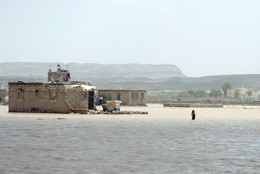 في الصورة الملتقطة يوم 23 أغسطس 2022، رجل يقف وسط مياه الفيضانات عقب سقوط أمطار غزيرة في ناحية مابار بمحافظة ذمار في اليمن. (شينخوا)