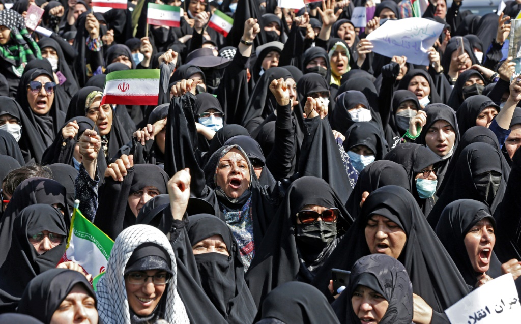 إيرانيون يلوحون بالعلم الإيراني خلال مسيرة مؤيدة لوضع الحجاب في طهران في 23 أيلول/سبتمبر 2022 (ا ف ب)