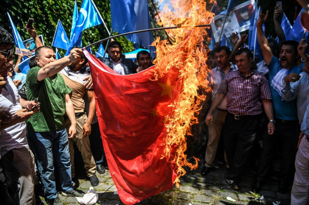   أنصار أقلية الأويغور المسلمة والقوميين الأتراك يحرقون العلم الصيني خلال مظاهرة (أ ف ب)
