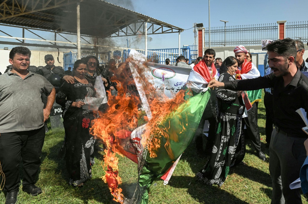 أشخاص يحرقون العلم الإيراني خلال مظاهرة تندد بوفاة مهسا أميني خارج مكاتب الأمم المتحدة في أربيل في 24 أيلول/سبتمبر 2022 (ا ف ب)