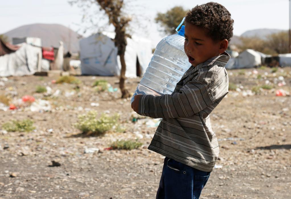 طفل يحمل زجاجة مياه في مخيم ضروان للنازحين داخل البلاد بالقرب من العاصمة اليمنية صنعاء يوم 25 مارس 2022. (شينخوا)