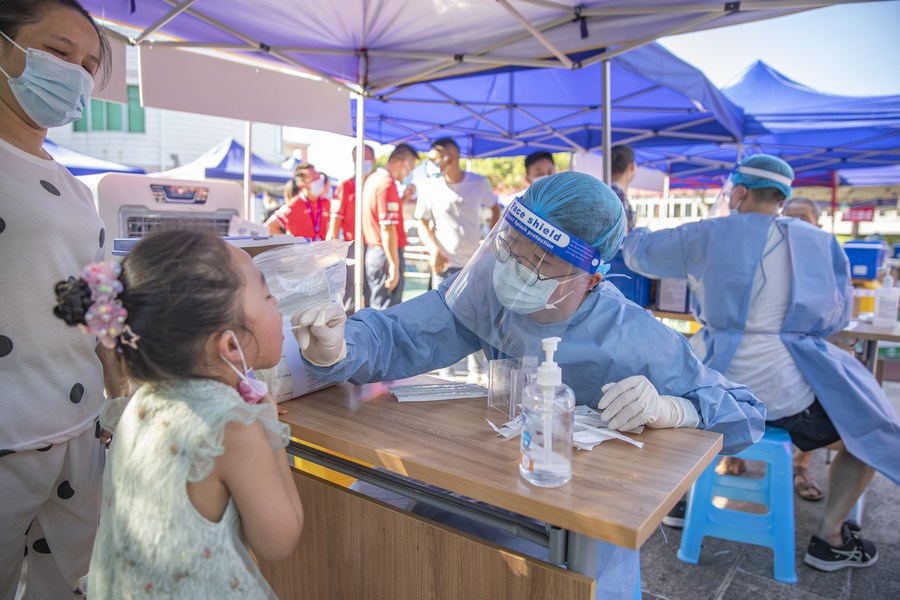 عامل طبي يأخذ عينة مسحة الحلق من طفلة لاختبار الحمض النووي للكشف عن كوفيد-19، وذلك في حي ليانغجيانغ الجديد ببلدية تشونغتشينغ بجنوب غربي الصين. (صورة أرشيفية، شينخوا)