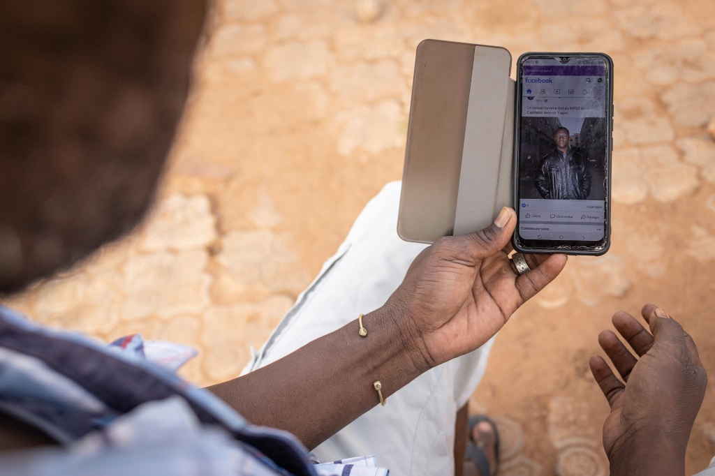 صورة الرجل القوي الجديد في بوركينا فاسو إبراهيم تراوري تظهر على شاشة هاتف يحمله رجل في العاصمة واغادوغو بتاريخ 1 تشرين الأول/أكتوبر 2022 (ا ف ب)