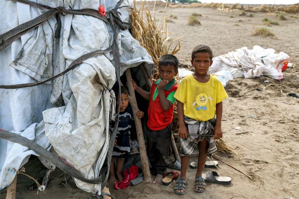 صورة التُقطت في 19 آب/أغسطس لأطفال يقفون خارج خيمة في مخيم للنازحين تضرر من السيول في منطقة الجراحي التي دمرتها الحرب بمحافظة الحديدة غرب اليمن (ا ف ب)