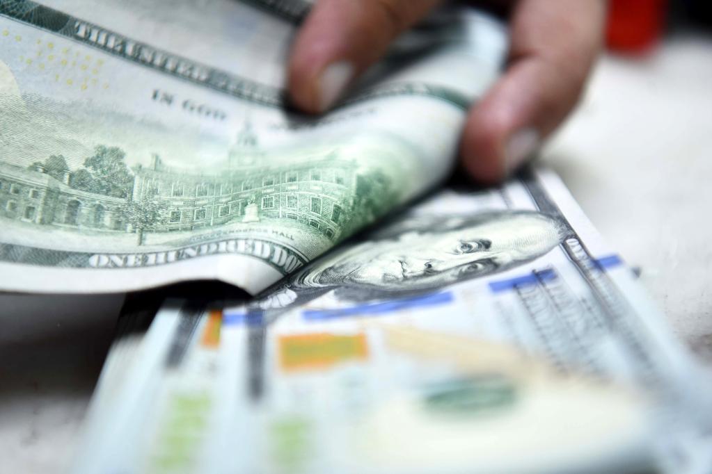 صيرفي يقوم بعدّ أوراق نقدية من عملة الدولار الأمريكي في روالبندي بباكستان في 29 يوليو 2022. (شينخوا)