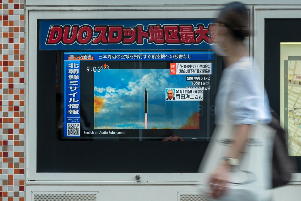 امرأة تسير في طوكيو أمام شاشة تبثّ لقطات من التلفزيون الوطني لإطلاق كوريا الشمالية صاروخاً في 4 ت1/أكتوبر 2022 (ا ف ب)