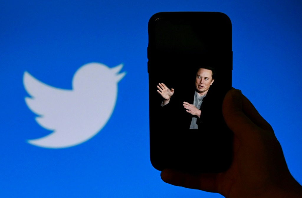 هاتف تظهر على شاشته صورة إيلون ماسك فيما يبرز في الخلفية شعار تويتر، الصورة التُقطت في الرابع من تشرين الأول/أكتوبر في واشنطن (أ ف ب)