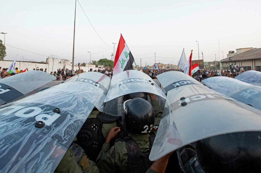 قوات الأمن العراقية تحتمي بالدروع خلال تجمع حاشد لإحياء ذكرى مرور ثلاث سنوات على اندلاع تظاهرات على مستوى البلاد ضد الفساد المستشري، في مدينة البصرة الجنوبية في 1 تشرين الأول/أكتوبر 2022 (ا ف ب)