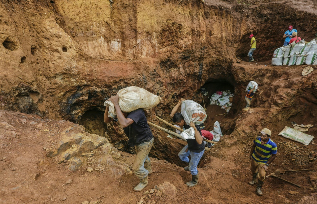 عمال المناجم يحملون أكياسًا بها صخور لسحقها لاستخراج الذهب من منجم بالقرب من روزيتا في شمال شرق نيكاراغوا. (أ ف ب)
