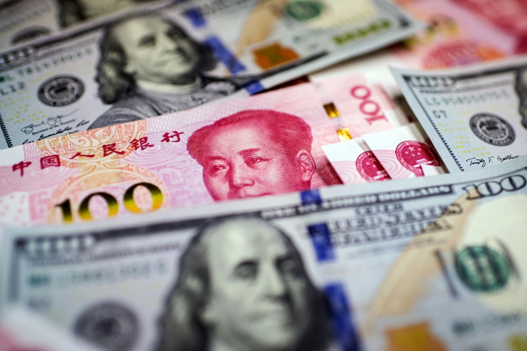 صورة تعبيرية تظهر فيها ورقة نقدية من فئة 100 يوان (باللون الأحمر) بين أوراق أخرى من فئة 100 دولار، في بكين في 14 كانون الثاني/يناير 2020 (ا ف ب)