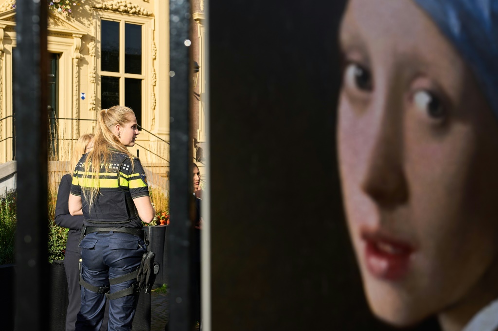 صورة التقطت في 27 تشرين الأول/أكتوبر 2022 لشرطية تقف أمام متحف موريتشيس في لاهاي (هولندا) فيما بدت إلى اليمين لوحة الفتاة ذات القرط اللؤلؤي" التي رسمها يوهانس فيرمير (ا ف ب)