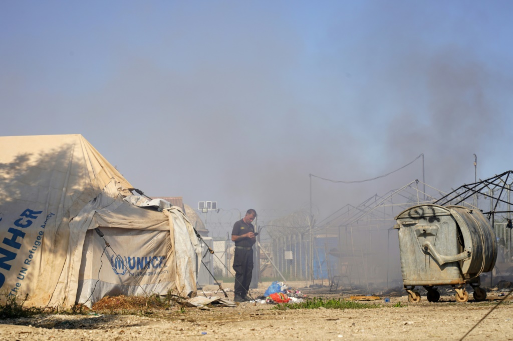    الدخان يتصاعد بعد اشتباكات اندلعت في مخيم للمهاجرين على حافة العاصمة القبرصية نيقوسيا يوم الجمعة (ا ف ب)   