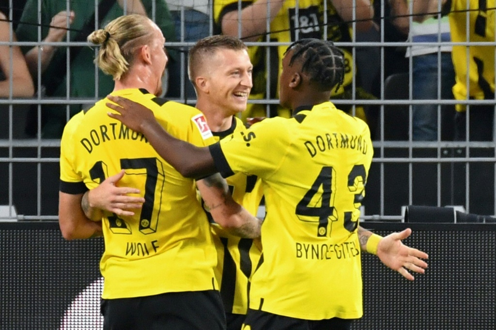 مهاجم بوروسيا دورتموند ماركو رويس (وسط) محتفلاً مع زميليه ماريوس وولف (يسار) والإنكليزي جايمي باينو-غيتينز بتسجيل هدف الفوز لفريقه أمام هوفنهايم في 2 أيلول/سبتمبر 2022 (ا ف ب)