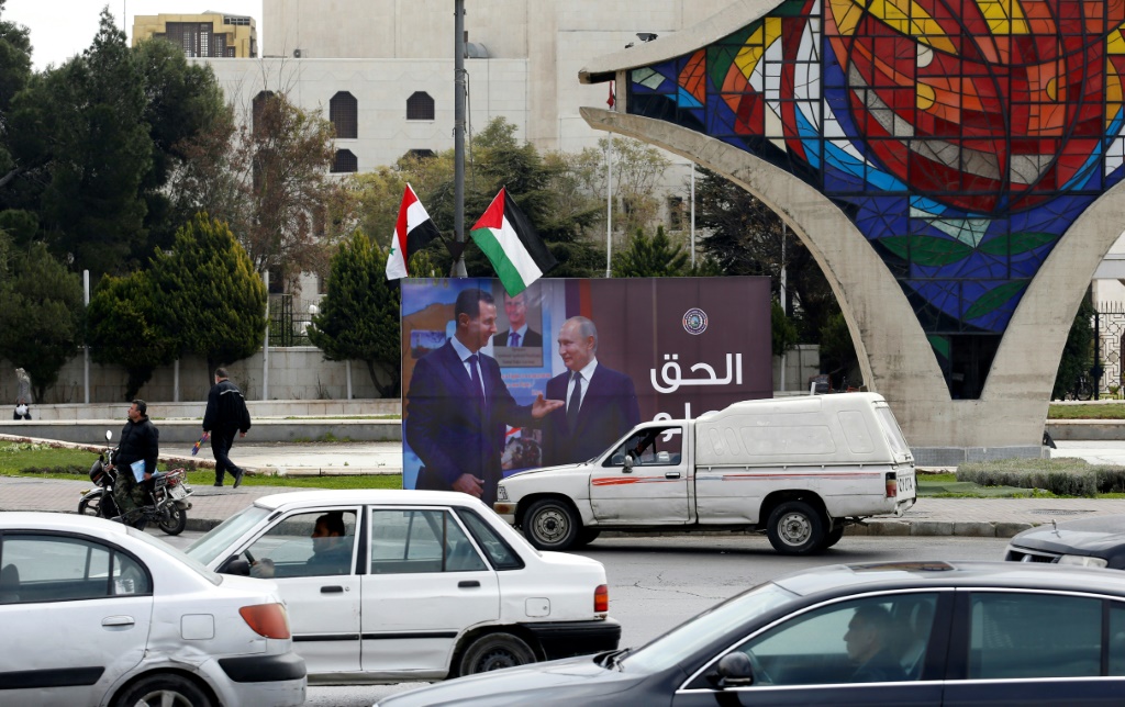 صورة عملاقة مرفوعة في ساحة الأمويين في دمشق في 8 آذار/مارس 2022، يظهر فيها الرئيس السوري بشار الأسد متحدثاً مع نظيره الروسي فلاديمير بوتين (أ ف ب)