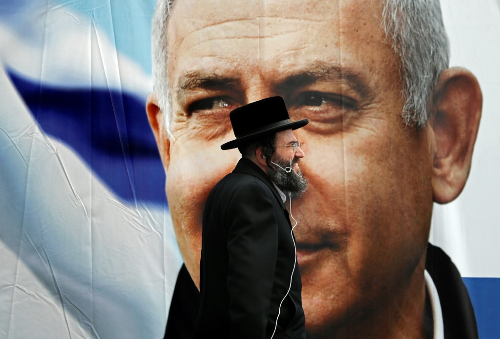 صورة من الأرشيف ملتقطة في الأول من نيسان/أبريل 2019 تظهر يهوديا متشددا يمر أمام لوحة اعلانية لبنيامين نتانياهو الذي كان رئيسا للوزراء في القدس (ا ف ب)