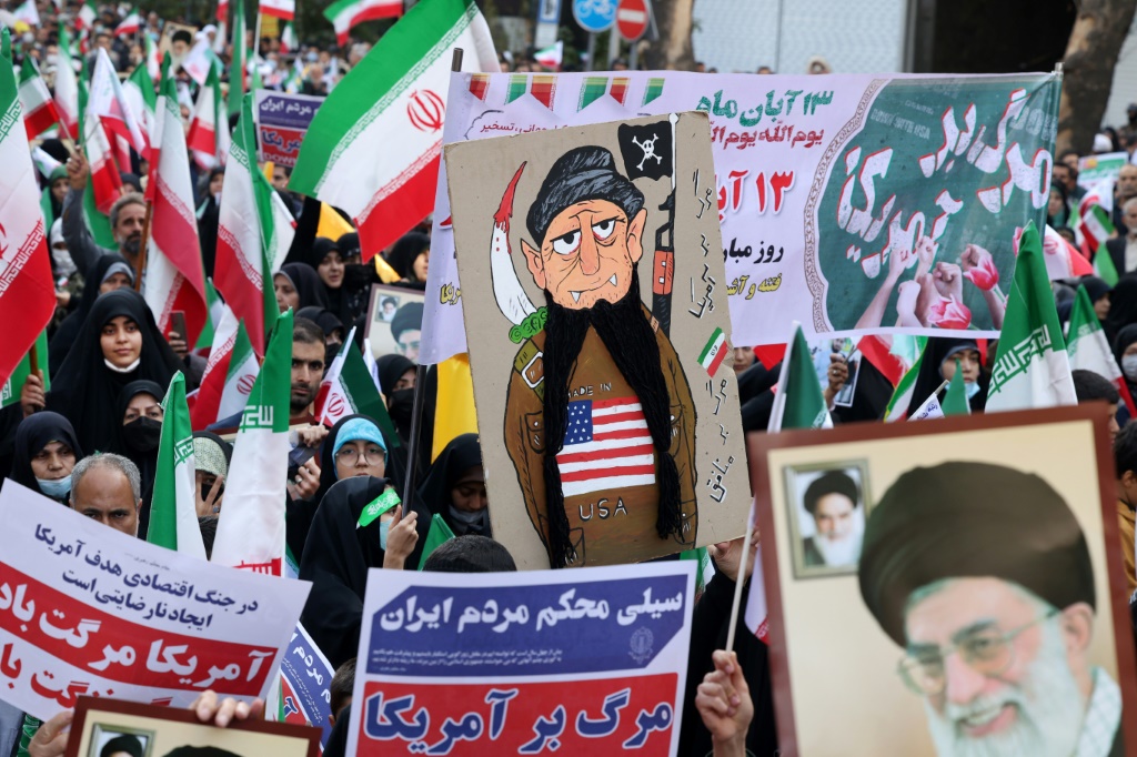 إيرانيون يلوحون بعلم بلادهم في مسيرة خارج السفارة الأمريكية السابقة في طهران (ا ف ب)