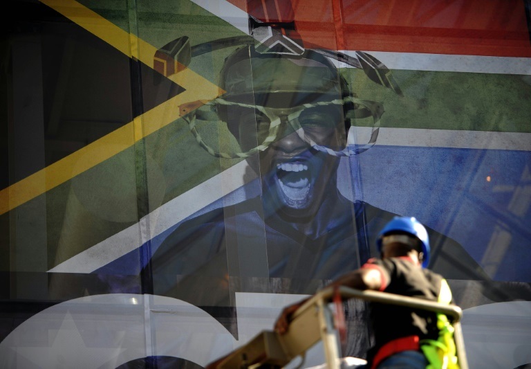 رجل بجانب أحد جدران جوهانسبرغ رُفع عليه علم جنوب إفريقيا قبل أيام على انطلاق بطولة كأس العالم لكرة القدم عام 2010، الصورة التُقطت في السابع من حزيران/يونيو 2010 (أ ف ب)