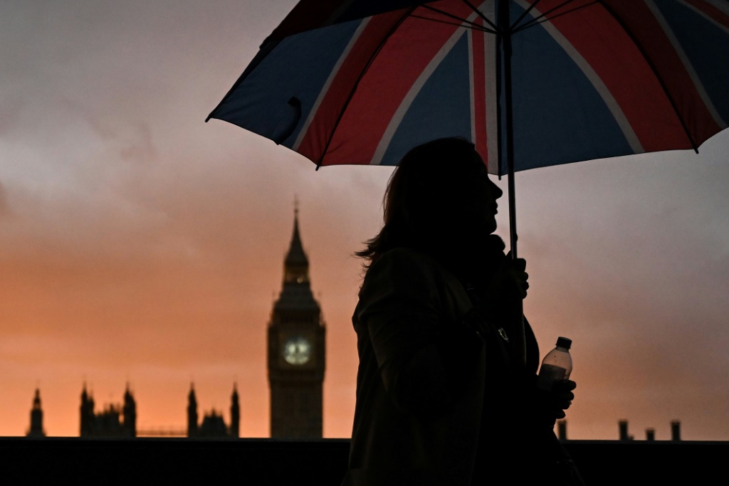 صورة مؤرخة في 18 أيلول/سبتمبر 2022 لامرأة تحمل مظلة بعلم المملكة المتحدة في لندن (ا ف ب)