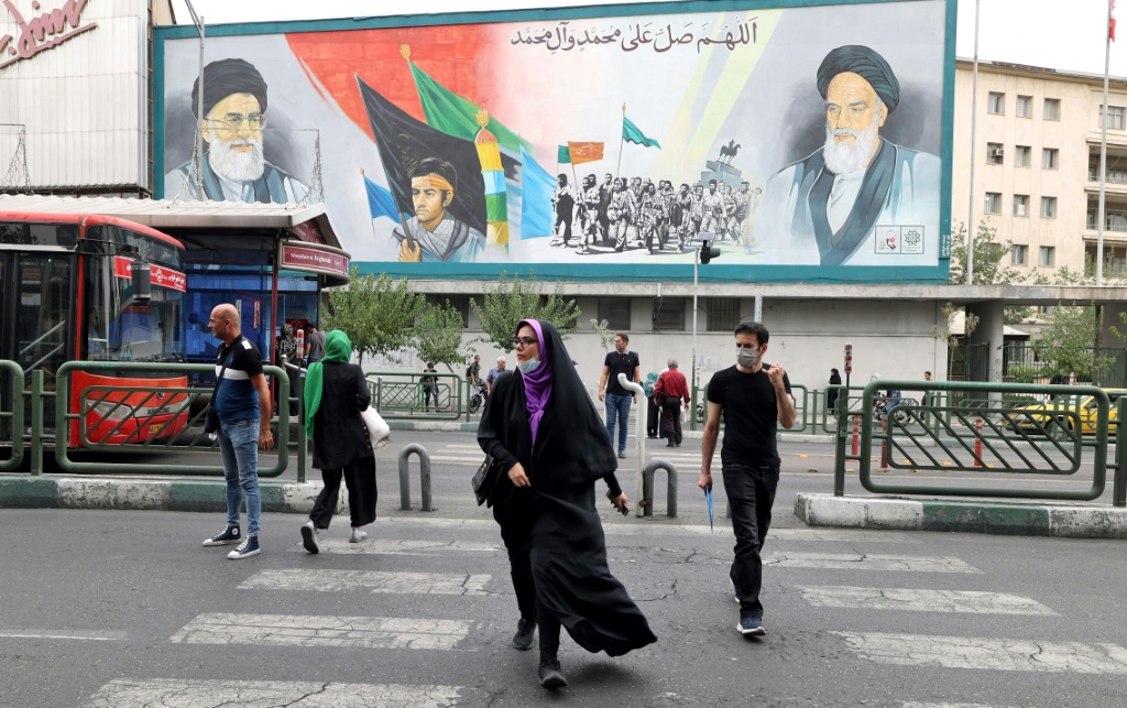 الإيرانيون يمررون لوحة إعلانية تظهر المرشد الأعلى لإيران آية الله علي خامنئي وآية الله روح الله الخميني (يمين) في طهران ، قبل بدء الحركة الاحتجاجية المناهضة للنظام في سبتمبر 2022 (أ ف ب)
