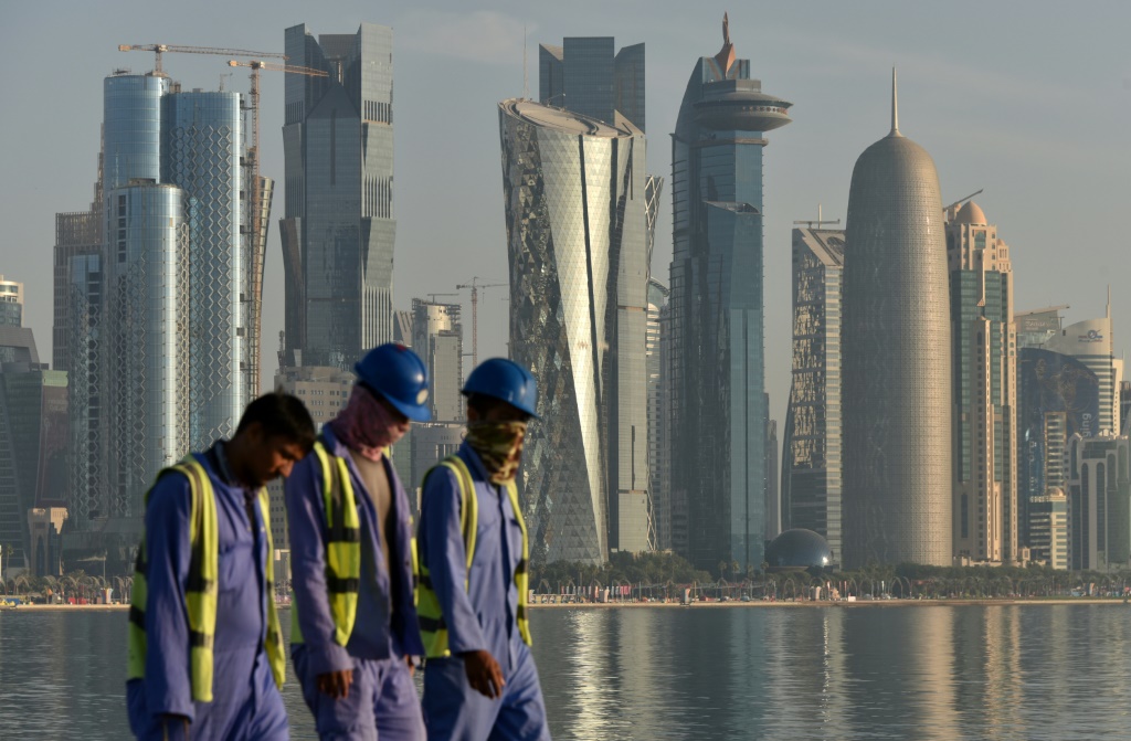 صورة لعمال يمشون على كورنيش قطر (ا ف ب)