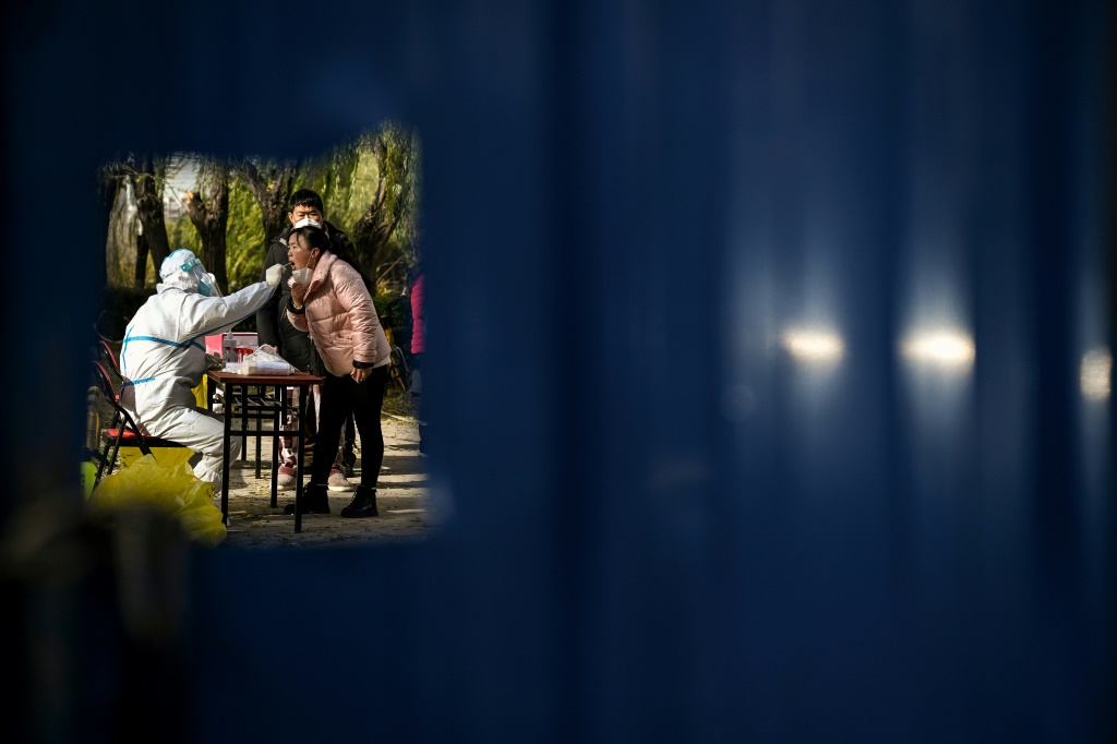 عامل صحي يجري فحصا لامراة في منطقة سكنية خاضعة للحجر الصحي في إطار مكافحة كوفيد-19 في بكين في 25 تشرين الثاني/نوفمبر 2022 (ا ف ب)