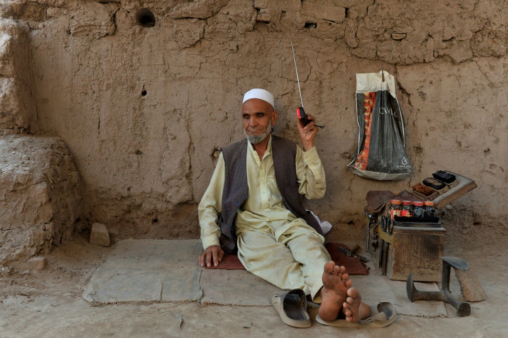 ماسح أحذية يستمع إلى مذياع في 2020 بالقرب من مدينة جلال أباد في أفغانستان (ا ف ب)