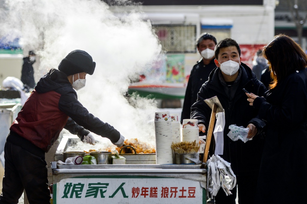سكان في أورومتشي عاصمة منطقة شينجيانغ في شمال غرب الصين، يشترون الطعام من بائع متجوّل في 1 كانون الأول/ديسمبر 2022 (ا ف ب)