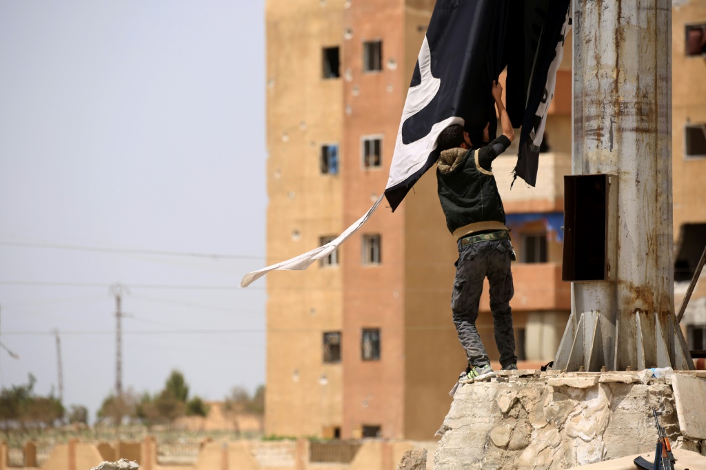     مقاتل كردي يزيل راية لتنظيم الدولة الإسلامية في مدينة الطبقة السورية في في 30 نيسان/أبريل 2017 (ا ف ب)