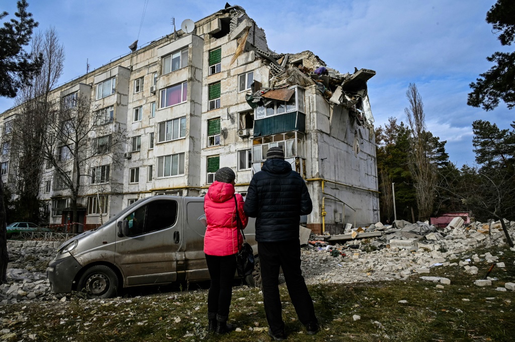 سكان محليون في قرية كلوهينو-باشكيريفكا في منطقة خاركيف ينظرون إلى مبنى سكني دمّرته ضربات في الثاني من كانون الأول/ديسمبر 2022 (أ ف ب)