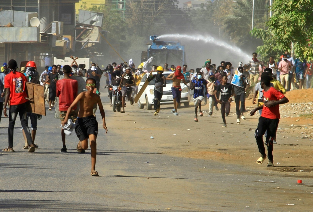  متظاهرون يفرون من خراطيم المياه التي أطلقتها شرطة مكافحة الشغب خلال اشتباكات مع قوات الأمن يوم الاثنين في الخرطوم (ا ف ب)
