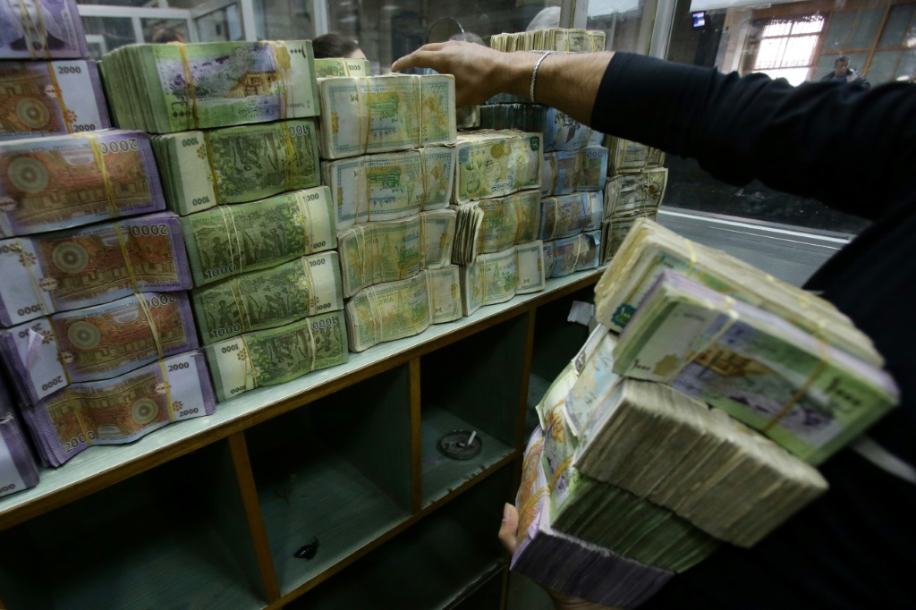    موظف يحمل رزماً من العملة السورية في 10 تشرين الثاني/نوفمبر 2022 داخل المصرف المركزي في دمشق (أ ف ب)