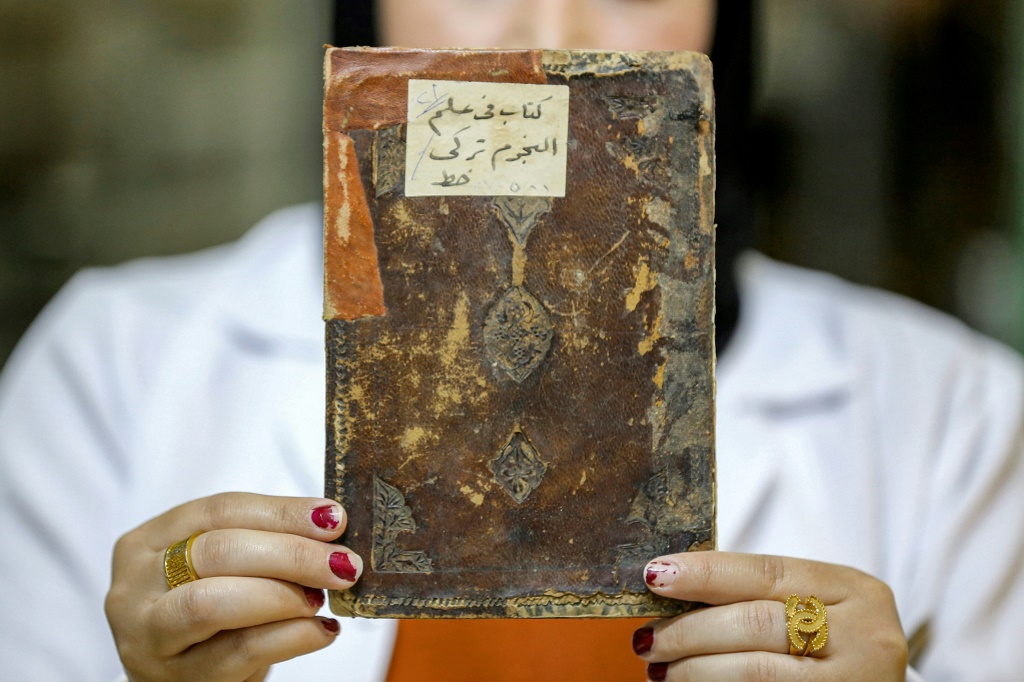 مخطوطة تخضع للترميم في دار المخطوطات في بغداد في السادس من كانون الأول/ديسمبر 2022 (ا ف ب)
