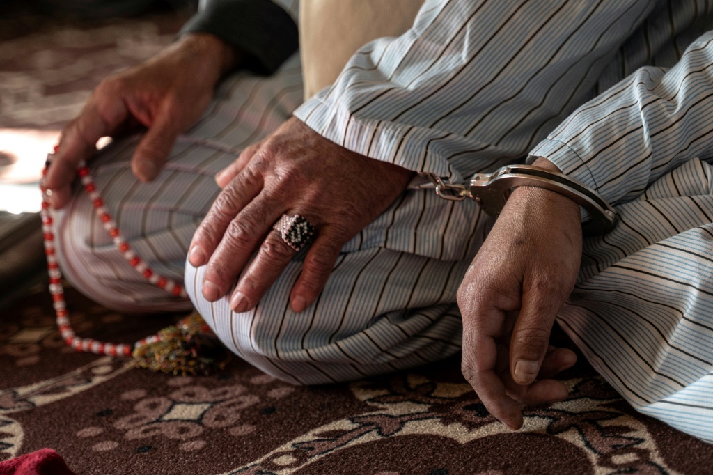   رجل أفغاني ، محكوم عليه بالإعدام بتهمة القتل ، يمسك سلسلة من المسبحة في يديه المكبلتين (أ ف ب)