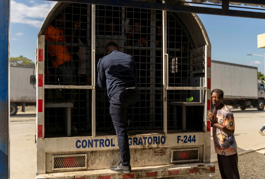عميل حدودي دومينيكي يفتح شاحنة تقل الهايتيين ليتم طردهم عند معبر بيلاديري الحدودي (أ ف ب)