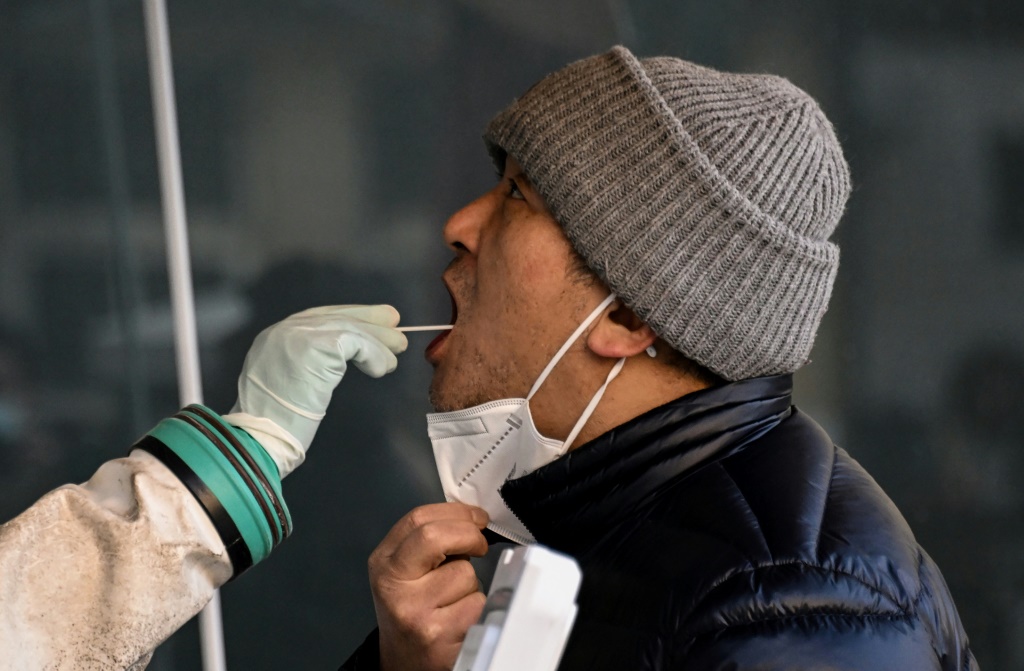 عامل صحي يأخذ عيّنة مسحة من رجل لفحصها بحثاً عن فيروس كورونا في مستشفى في بكين في 26 كانون الأول/ديسمبر 2022 (ا ف ب)