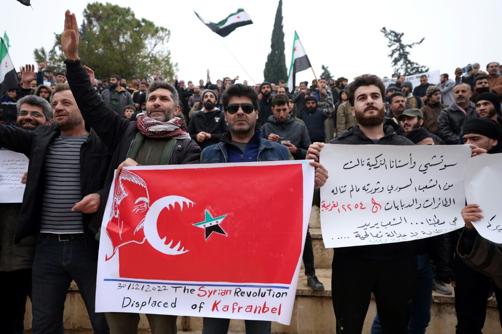    متظاهرون يرفعون أعلام المعارضة السورية ولافتات في إطار احتشادهم ضد تقارب محتمل بين تركيا والنظام السوري (أ ف ب)