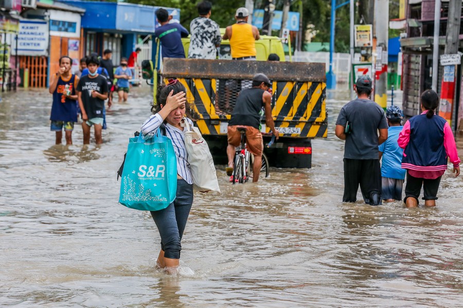 سكان يسيرون عبر مياه الفيضانات الناجمة عن العاصفة الاستوائية الشديدة نالجاي في مقاطعة كافيت في الفلبين يوم 30 أكتوبر 2022. (شينخوا)