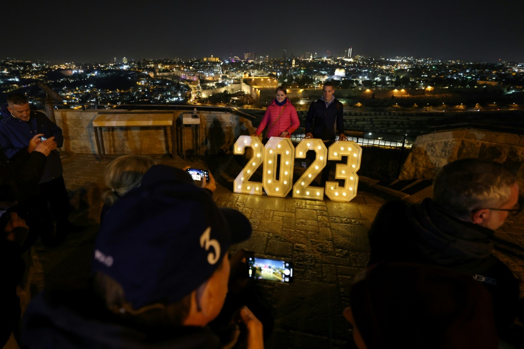 صورة مؤرخة في 31 كانون الاول/ديسمبر 2022 لشخصين أمام لاقتة مضيئة بأرقام العام الجديد في جبل الزيتون في القدس (ا ف ب)