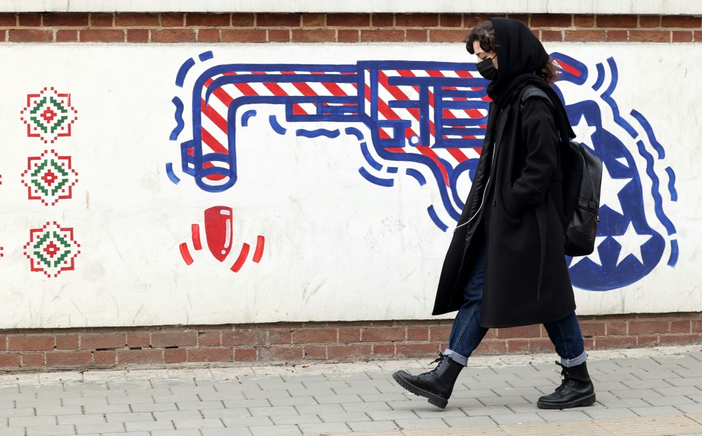    إيرانية تمر أمام رسم مندد بالولايات المتحدة على جدار السفارة الأميركية السابقة في طهران في 12 آذار/مارس 2022 (أ ف ب)