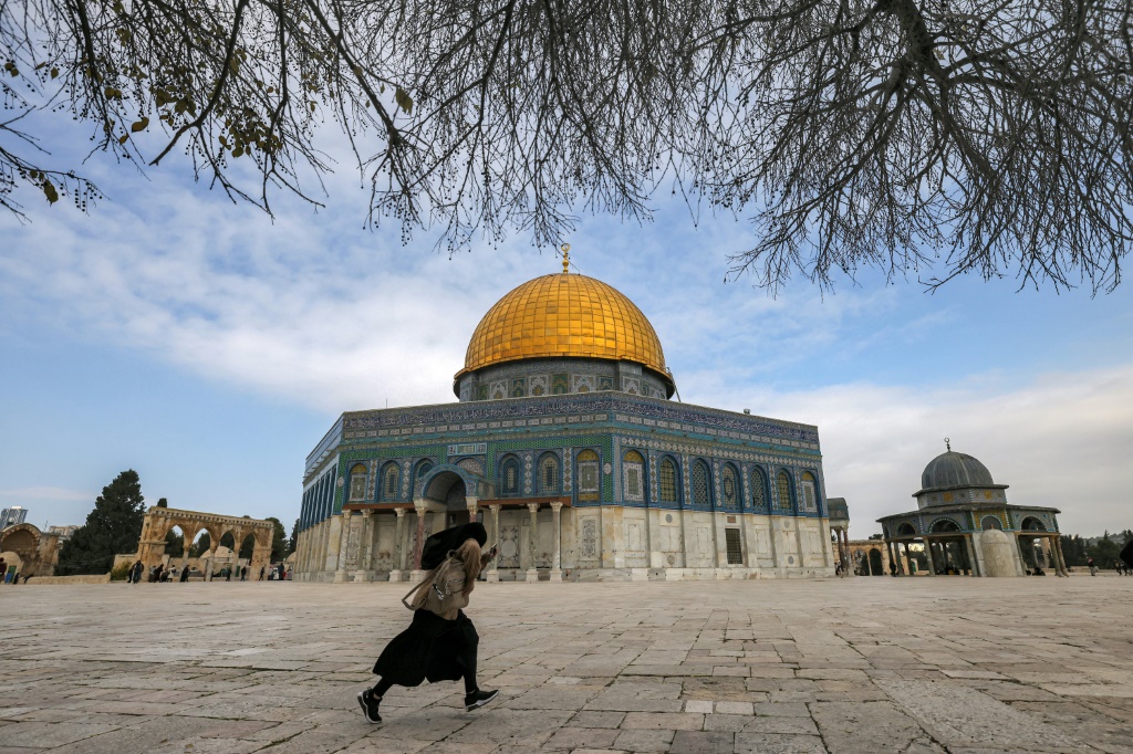 امرأة تجري بالقرب من ضريح قبة الصخرة في مجمع المسجد الأقصى ، المعروف باسم مجمع جبل الهيكل لدى اليهود ، في البلدة القديمة في القدس يوم 3 يناير (أ ف ب)