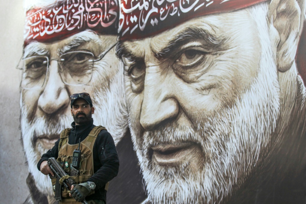 مقاتل من الحشد الشعبي يقف أمام لافتة ضخمة عليها صورة قائد فيلق القدس اللواء قاسم سليماني (ا ف ب)