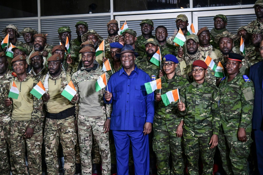 رئيس ساحل العاج الحسن واتارا يقف مع الجنود العاجيين المفرج عنهم بعد احتجازهم في مالي (ا ف ب)