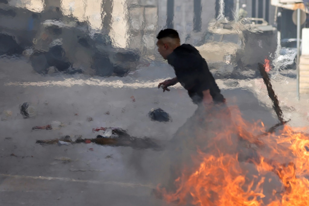 متظاهر فلسطيني يركض بين إطارات مشتعلة خلال مواجهات مع القوات الإسرائيلية خلال اقتحامها البلدة القديمة في مدينة نابلس شمال الضفة الغربية المحتلة في 30 كانون الاول/ديسمبر2022 (ا ف ب)