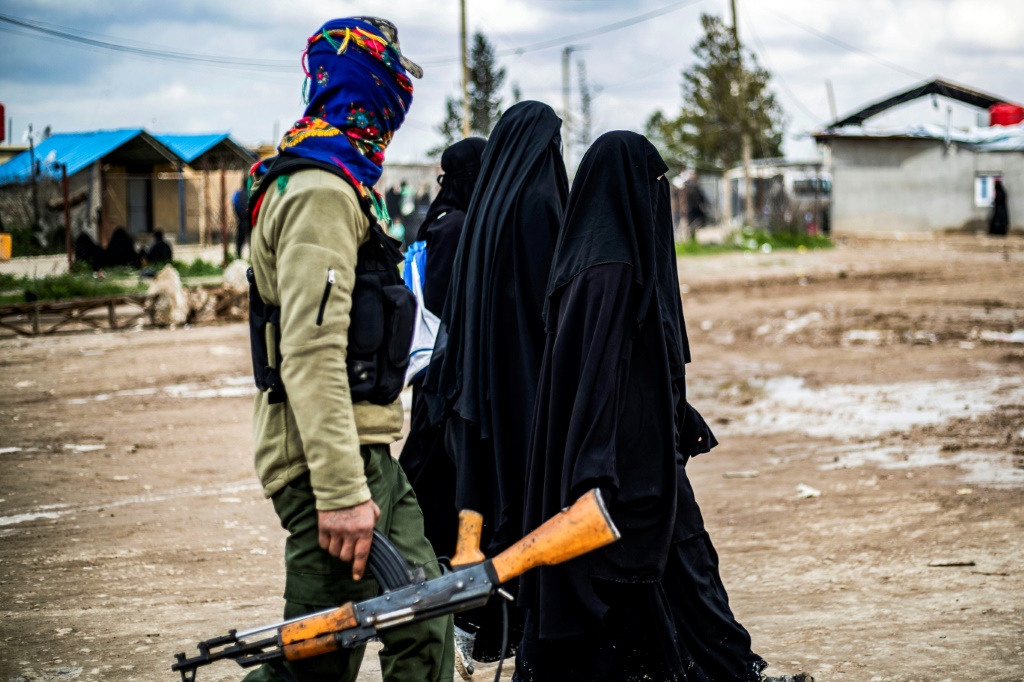 نساء في مخيم الهول يمشين تحت حراسة قوات سوريا الديمقراطية (ا ف ب)