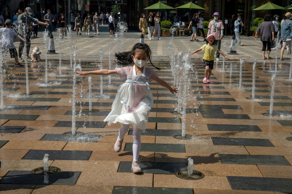 فتاة تركض عند نافورة مياه في العاصمة الصينية بكين في الأول من حزيران/يونيو 2021 (ا ف ب)