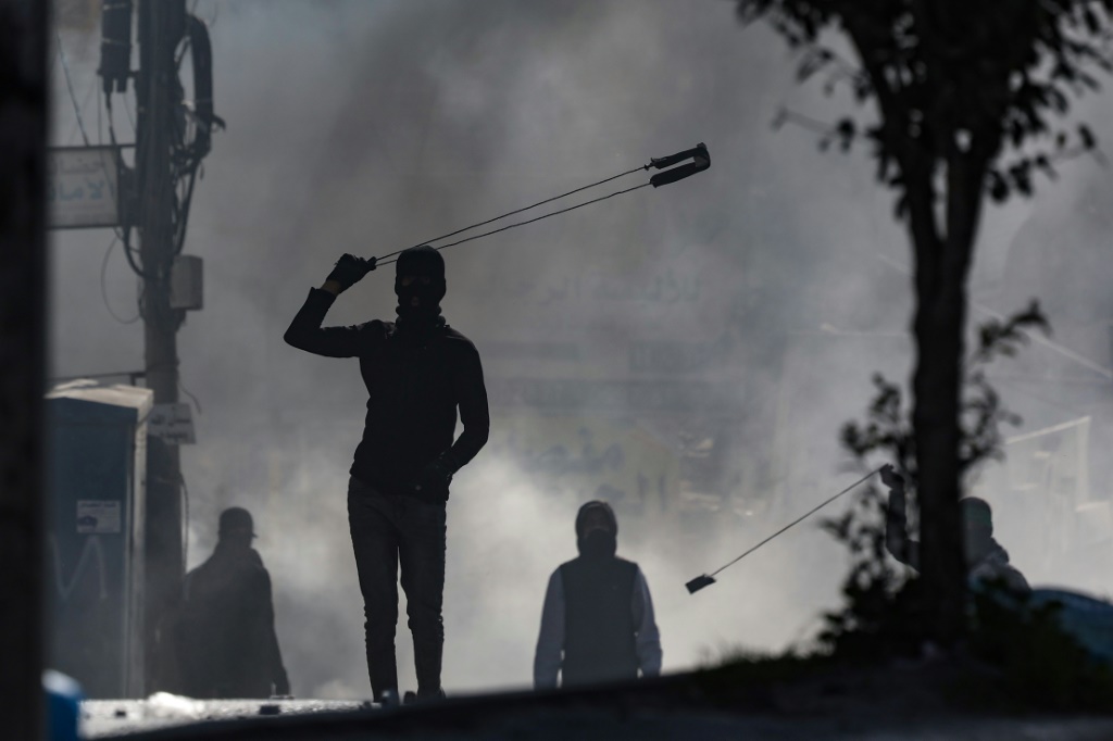متظاهرون يرشقون القوات الاسرائيلية بالحجارة في بلدة الرام بالضفة الغربية بينما يعبر الفلسطينيون عن غضبهم من غارة يوم الخميس الدامية في جنين (أ ف ب)