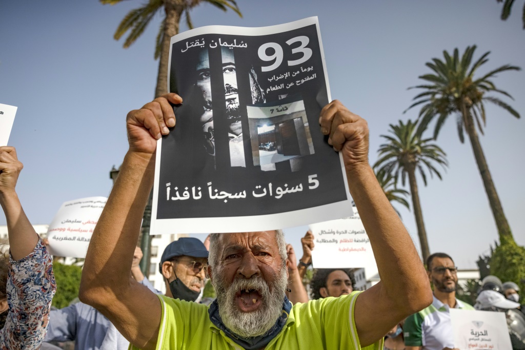  ناشطون يرفعون لافتة تحمل صورة سليمان الريسوني خلال تظاهرة مؤيدة للصحافي في الرباط بتاريخ 10 تموز/يوليو 2021 (ا ف ب)