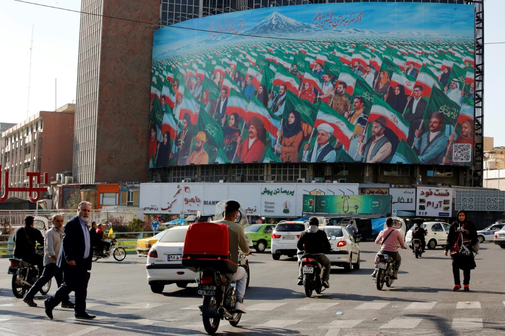    أشخاص يسيرون عبر معبر للمشاة في ساحة وليعصر وسط العاصمة الإيرانية طهران في 25 تشرين الأول/أكتوبر 2022 (أ ف ب)