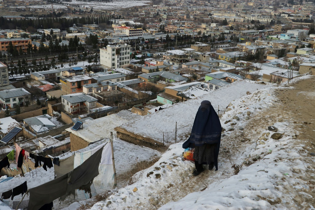    امرأة تسير على طريق خلال يوم شتاء بارد في فايز آباد بمقاطعة بدخشان في أفغانستان في 18 يناير 2023 (أ ف ب)