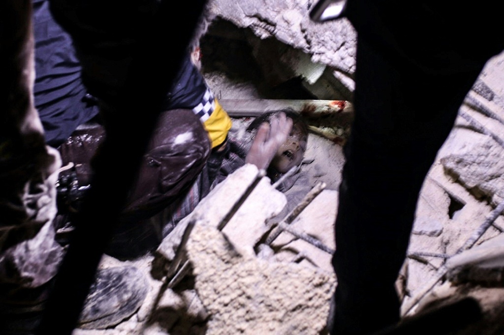 عناصر إنقاذ يحاولون انتشال فتى من تحت ركام مبنى انهار بعد الزلزال في اعزاز بتاريخ 6 شباط/فبراير 2023 (أ ف ب)